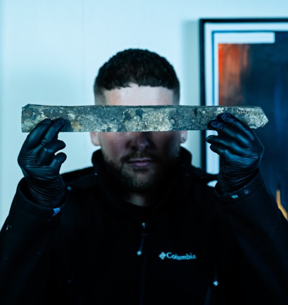 Man holding iron ore in front of his face